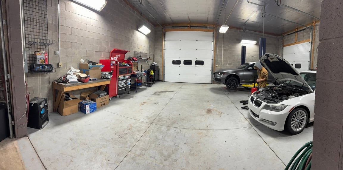 Wide workshop bay with several cars, including two with their hoods open