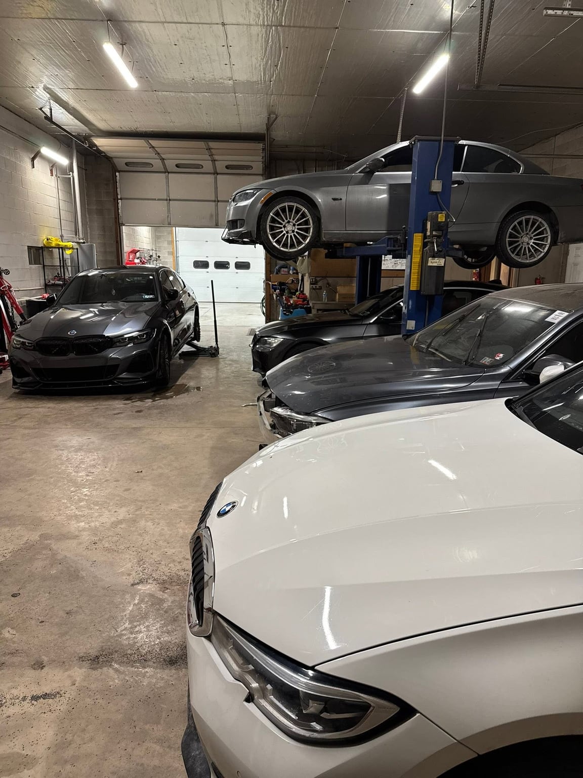 Workshop interior with several cars parked between vehicle lifts